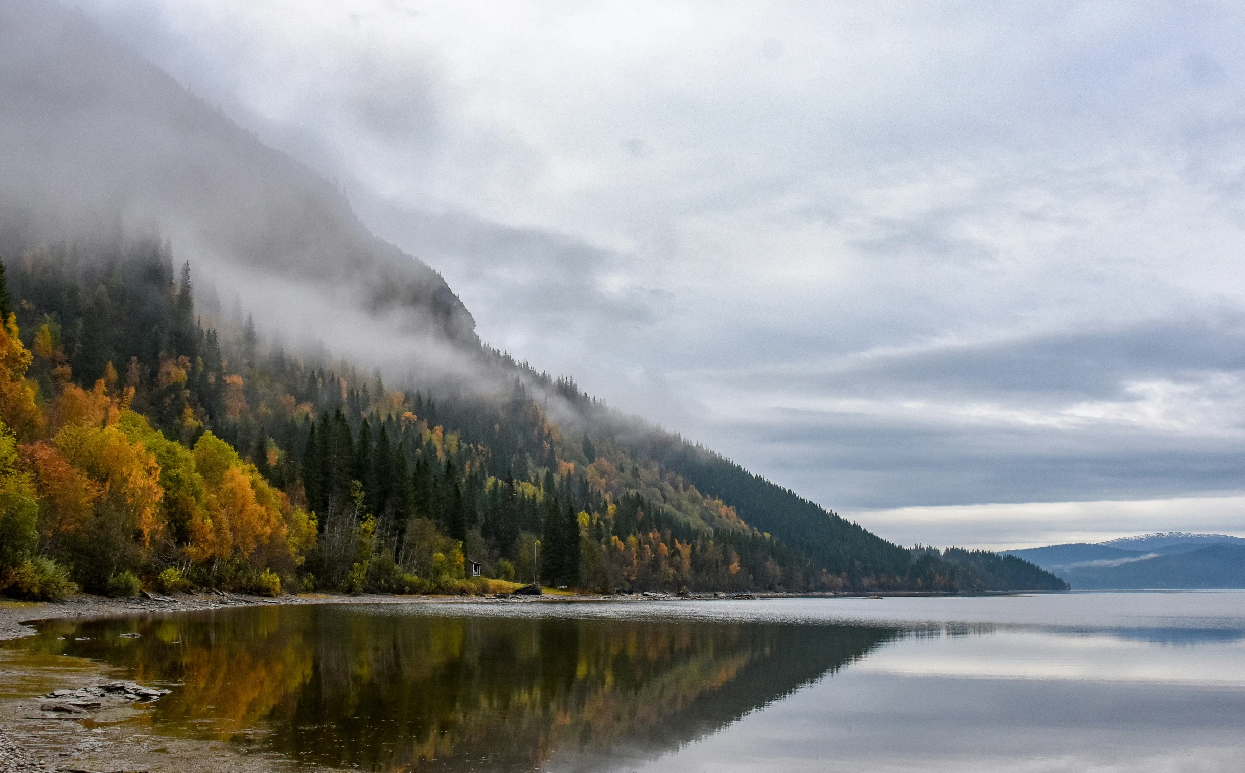 a scenic view of a large mountain range, water and trees