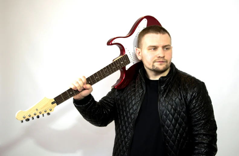 a man holding up his electric guitar with a devil like horn on it