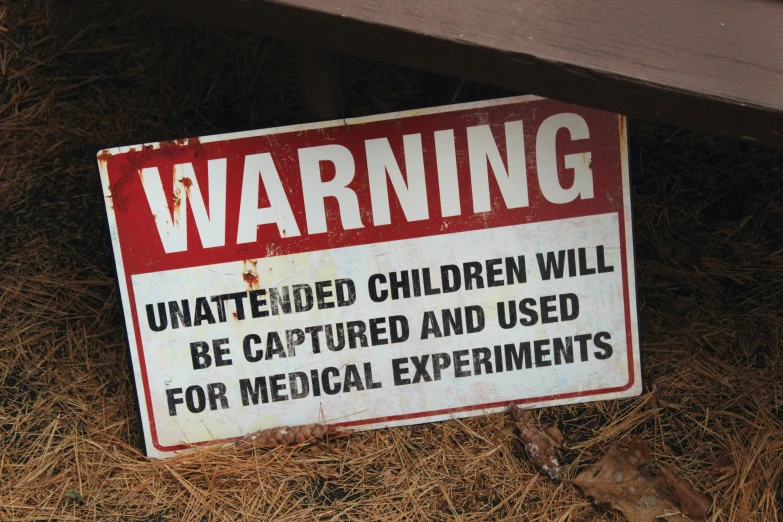 a warning sign sits on straw in front of a bench