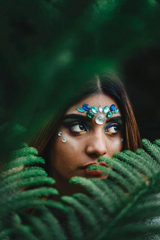 a woman with a blue eyeliner has leaves around her