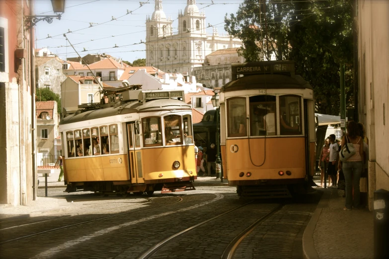 an orange and yellow trolley is driving past another light rail train