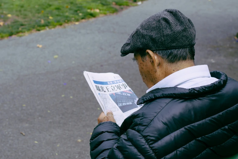 an older man wearing a hat reading a news paper