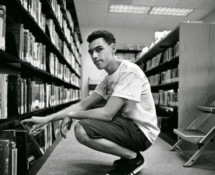 a person is squatted down and has books on shelves