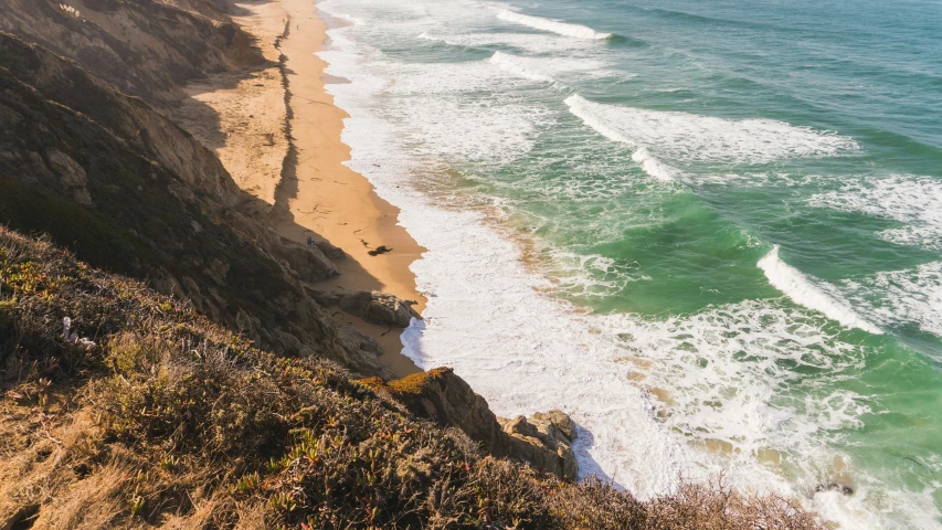 a view looking down on the coast with the crashing waves