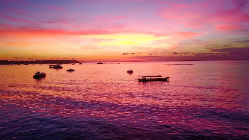 many small boats in a body of water under a colorful sky