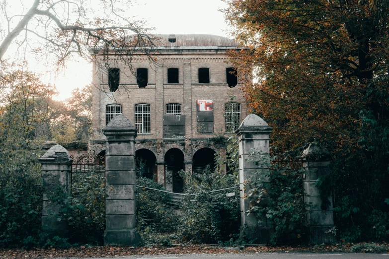 an old house sits between a brick wall and tree