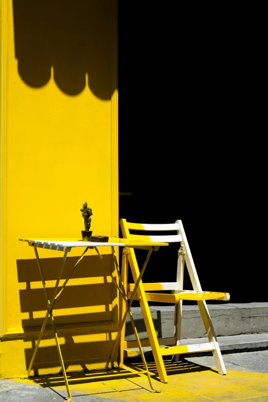 yellow wooden chairs and table are next to a wall