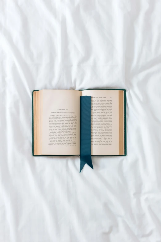 open book with ribbons on white sheet on bed