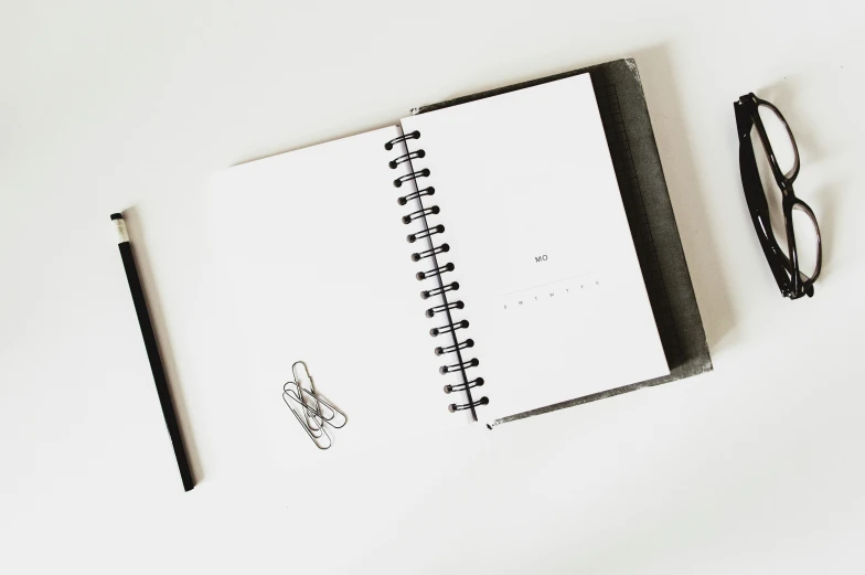 a notebook with glasses and pen on a white surface