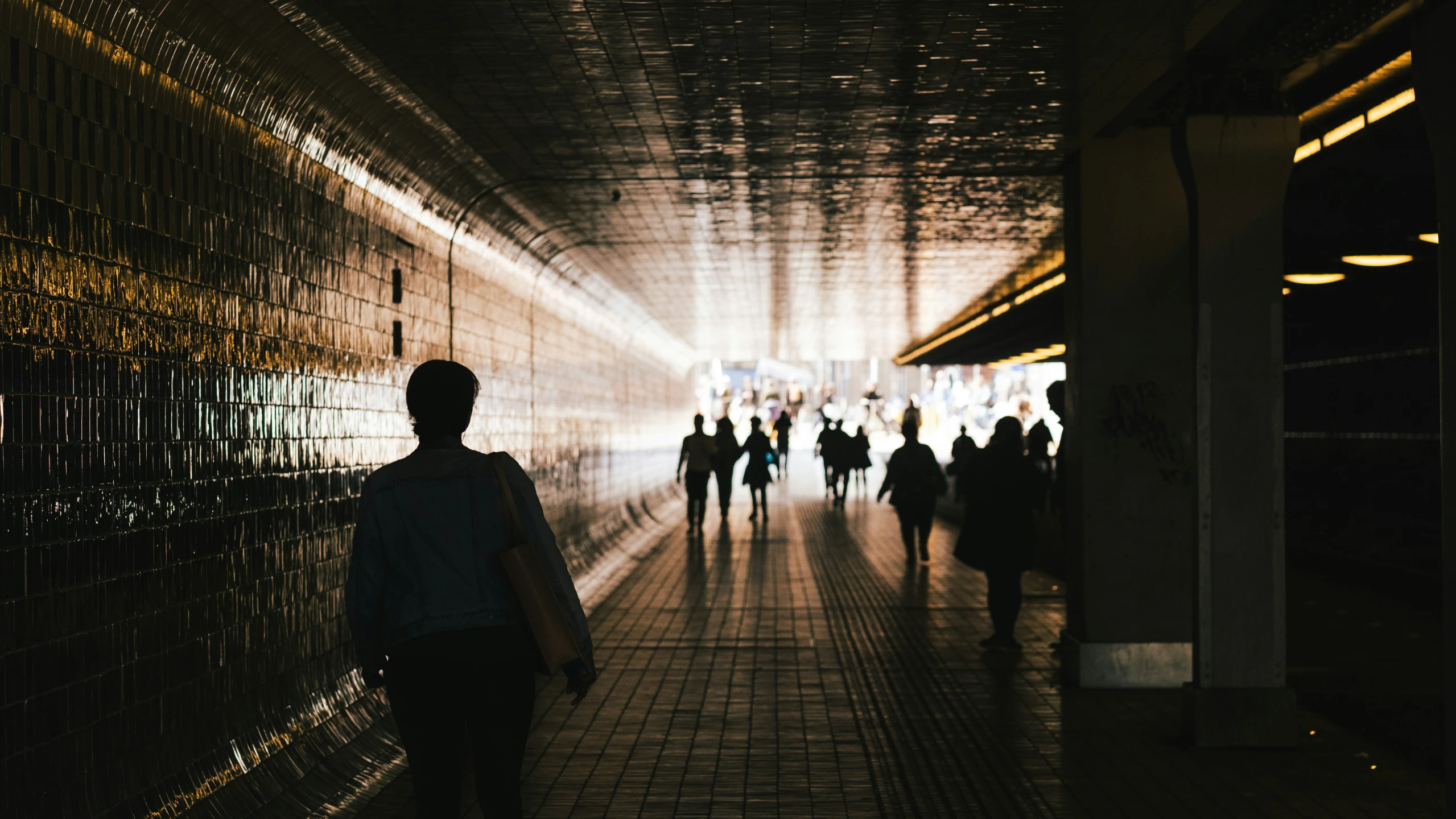 people walking in a tunnel that is full of lighting