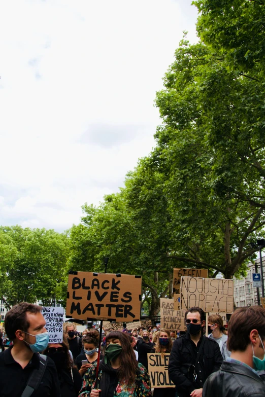 a crowd of people holding a protest sign in a park