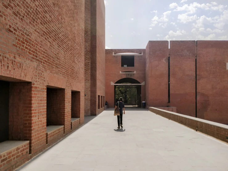 man walking down large walkway with brick buildings in background