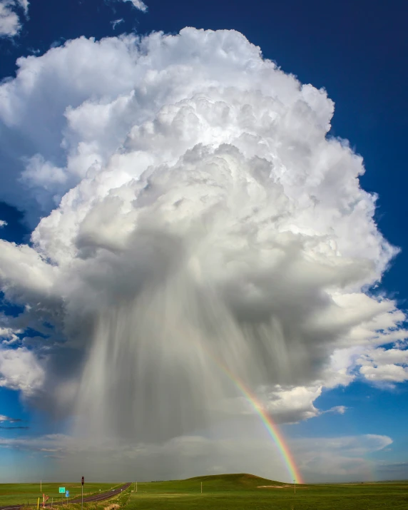 a huge cloud of rain appears over a lush green countryside