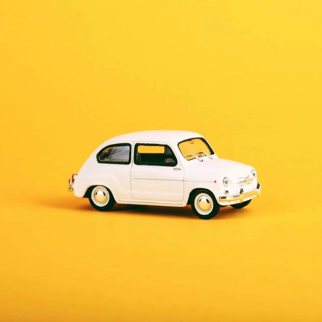 a small model car sits on a yellow background