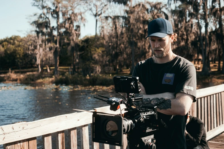 a person with a camera on a boardwalk by some water