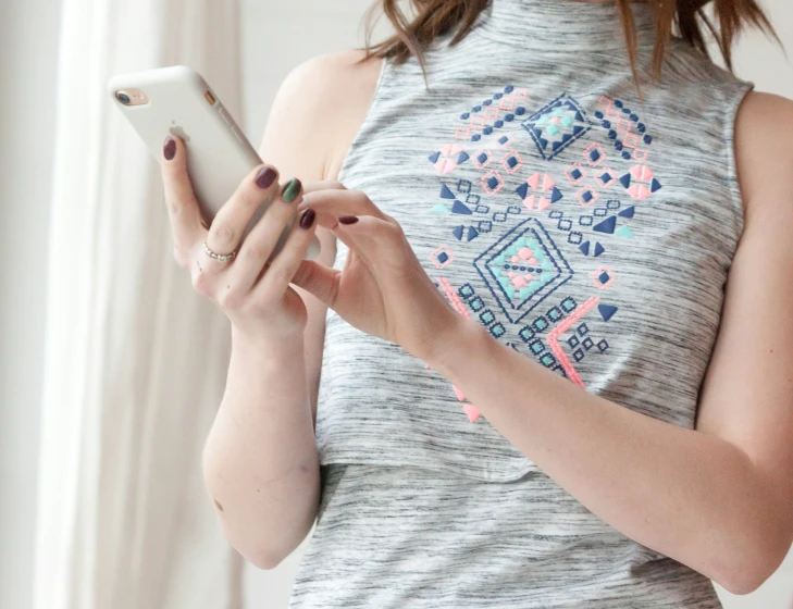 a woman in grey shirt holding a white cellphone