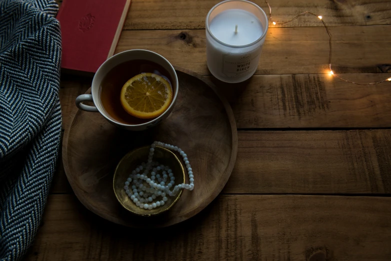 a plate filled with an orange next to a candle and some kind of bowl