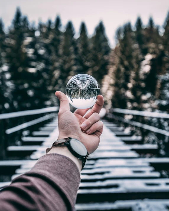 a person holding out their glass ball in the snow