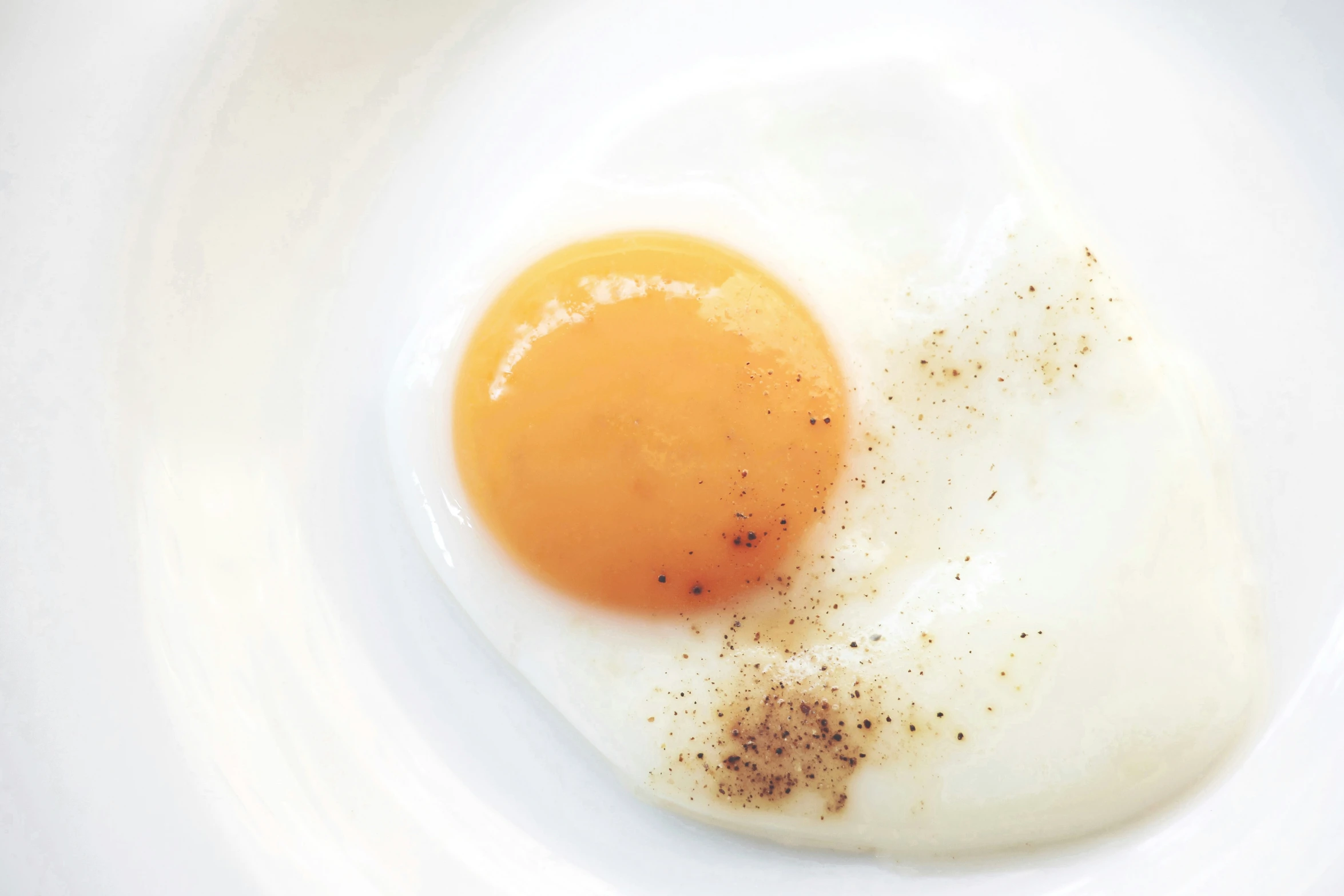 an egg sitting on a plate with black stuff