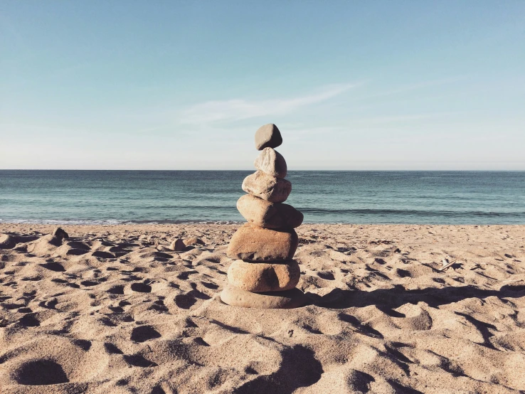 a pile of rocks sitting in the sand at the beach