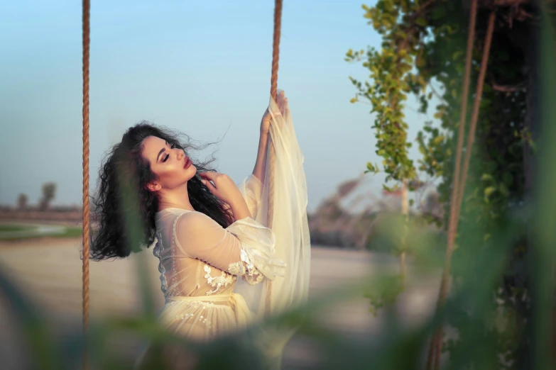 woman in vintage white dress swinging on swing