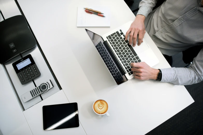 a man on a laptop with various objects on a table