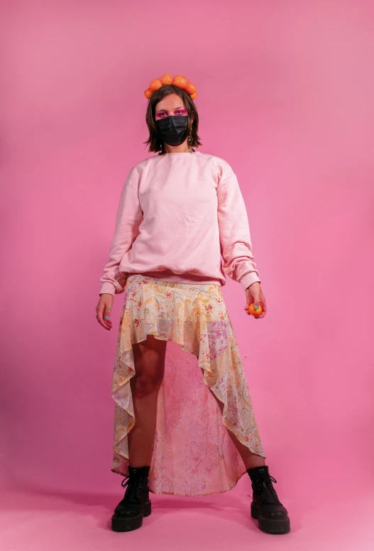 a woman in a pink sweatshirt and skirt with the face mask covering her eyes