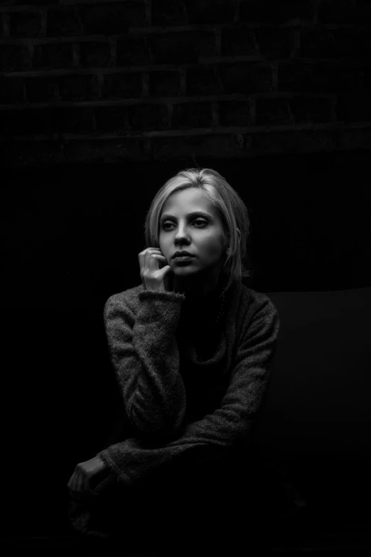 a black and white po of a girl sitting down talking on a cell phone