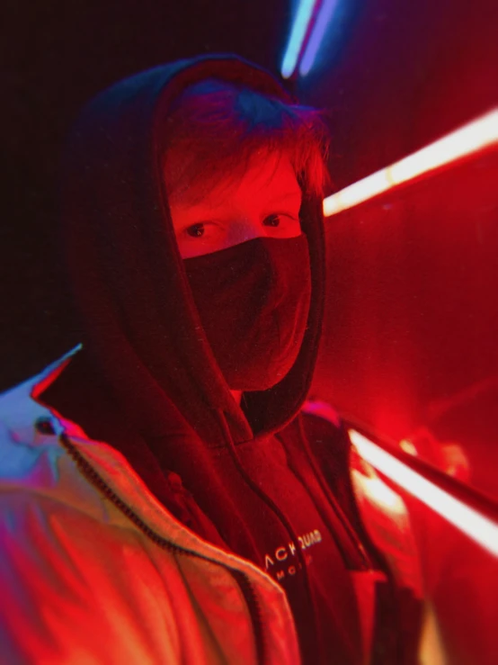 young man wearing hoodie standing in neon light