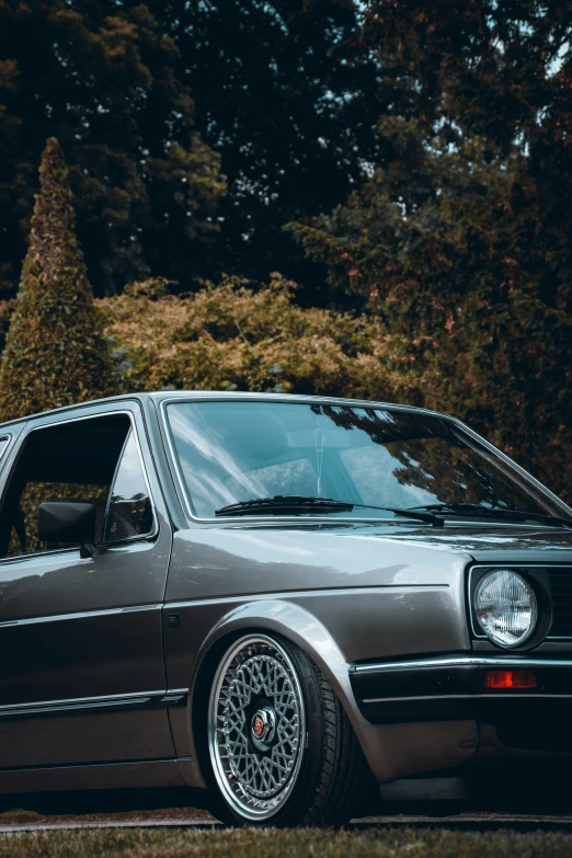 the black and silver station wagon is parked by some trees