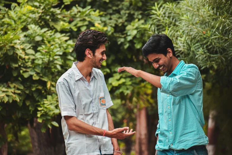 two men stand near each other pointing at soing