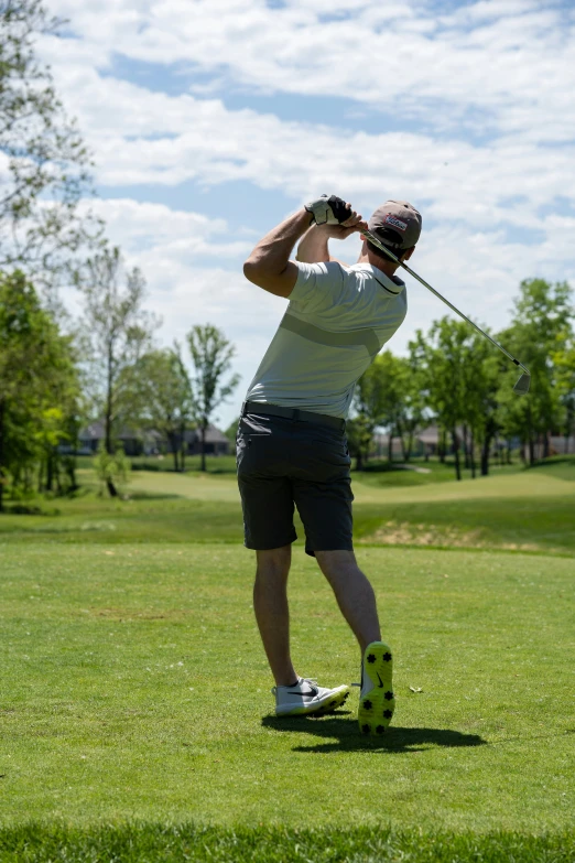 a man standing in the grass holding a golf club