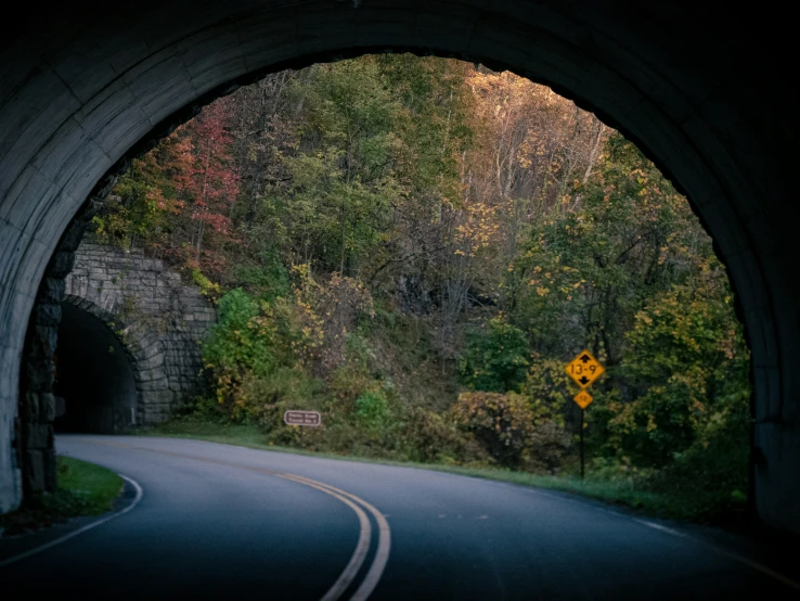 a curve in the road that leads to a tunnel in a hill