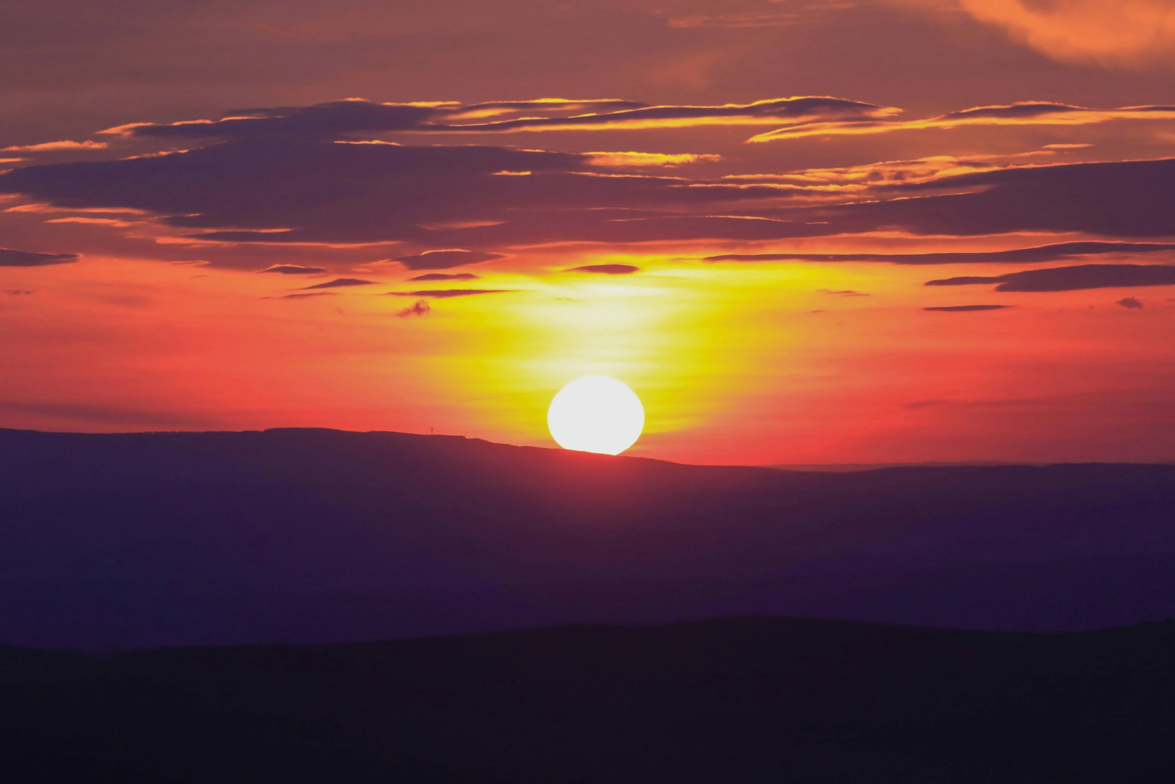 a sunset seen in the mountains over a valley