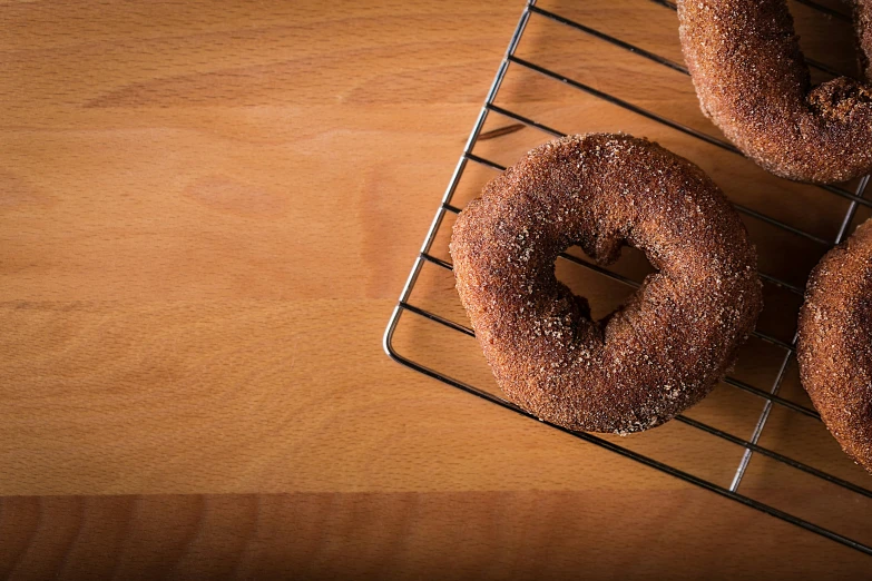 three donuts on a rack sitting on a wooden table