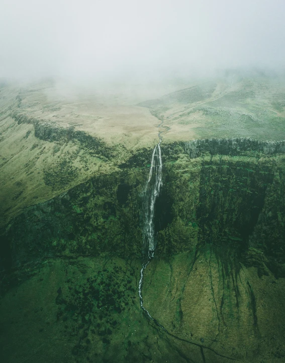 the waterfall is winding through a green valley