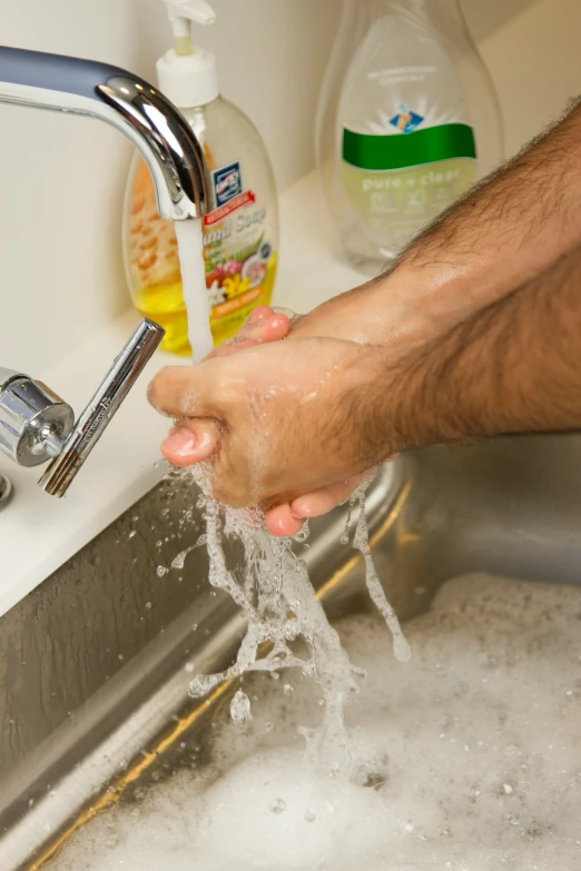 a person washing their hand in the kitchen sink