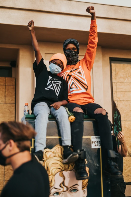 people sit on top of a stage with their arms in the air