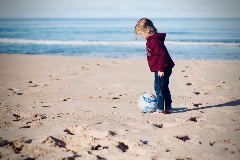 the child is playing with a ball on the beach