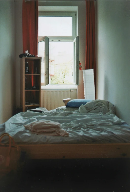 an empty bed sits in front of a window