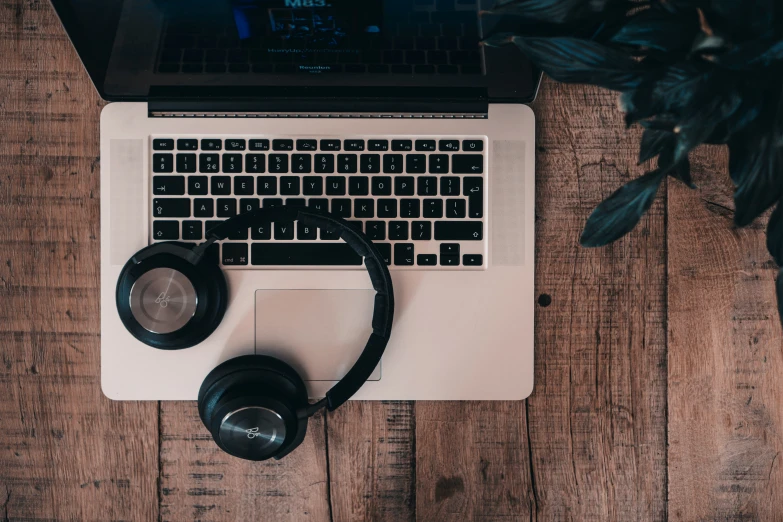 headphones on top of a laptop next to a keyboard