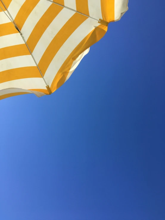 a yellow and white umbrella under the blue sky