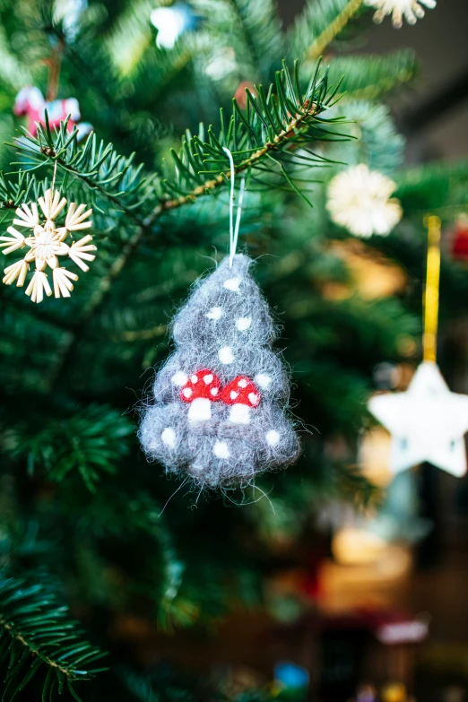 a christmas tree ornament hanging from the tip of a green christmas tree