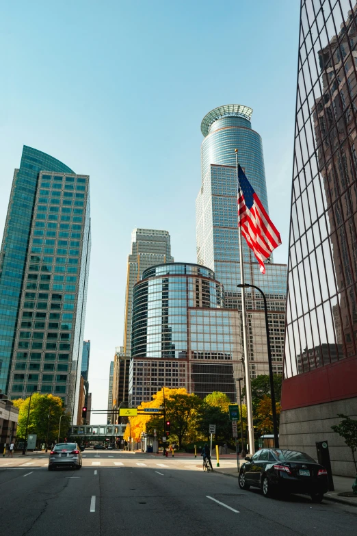 the american flag is hanging high on a city street