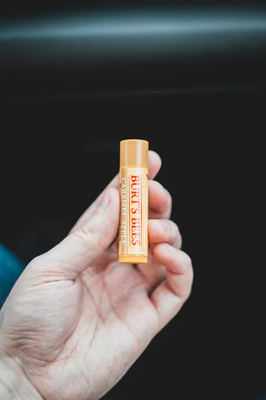 a person holding a small golden lip bale