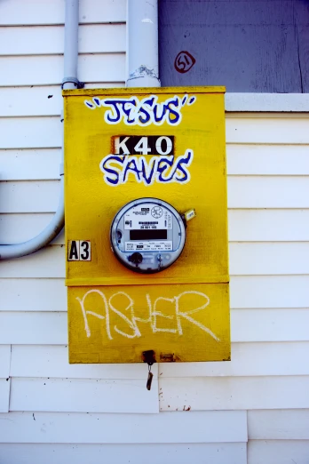 graffiti written on a wall next to a yellow meter