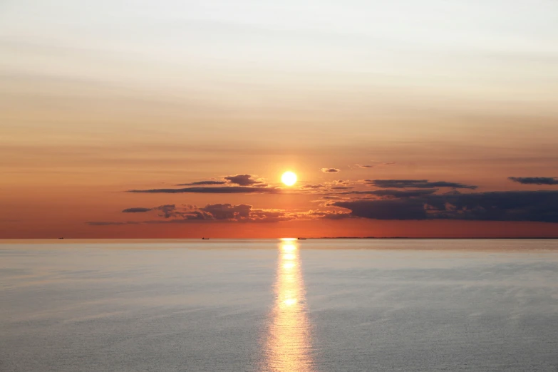 the sun is setting over a calm body of water