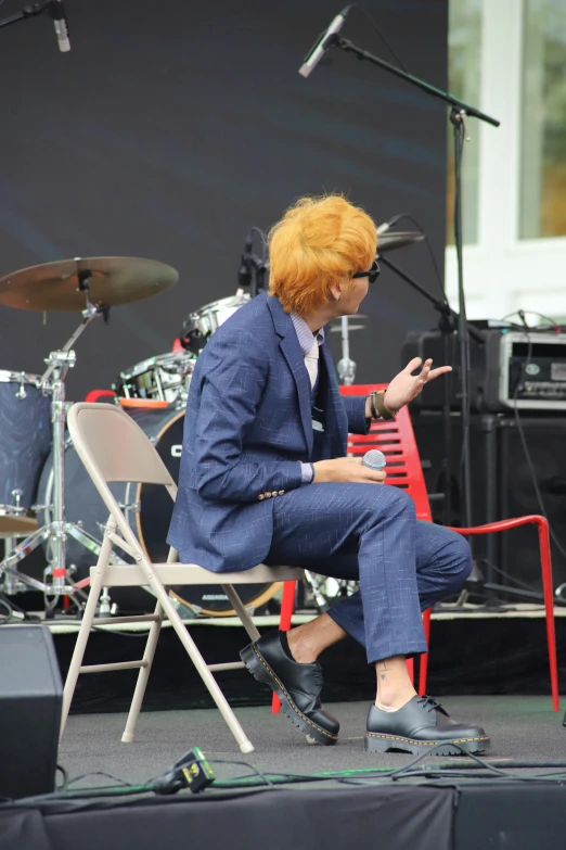 a red headed man in suit and glasses is on stage