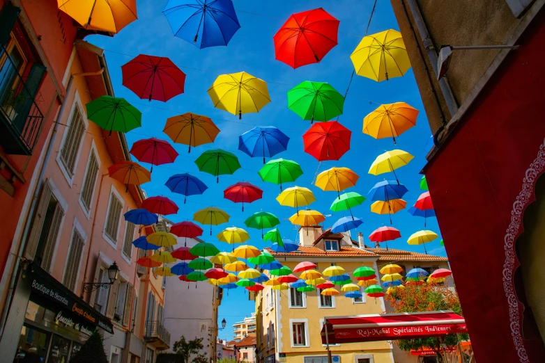 a bunch of colorful umbrellas are flying high above a town