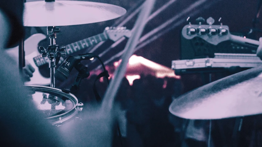 a man plays the drums on his set as another man watches